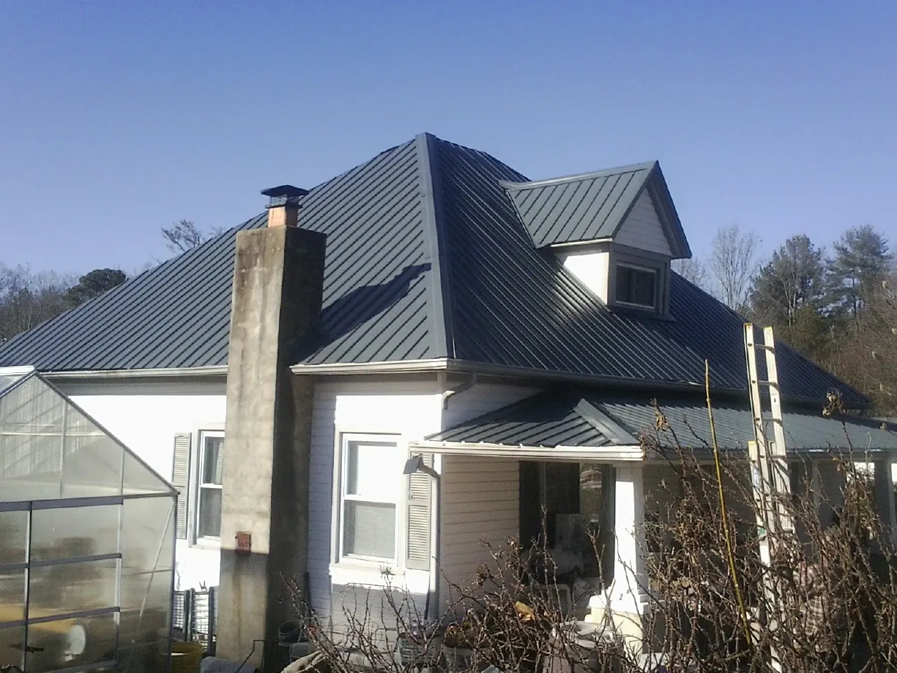 Dark blue standing seam metal roof on a white farmhouse with dormer — Slate & Tile Roof Repair by Roofing Brothers in Lynnwood