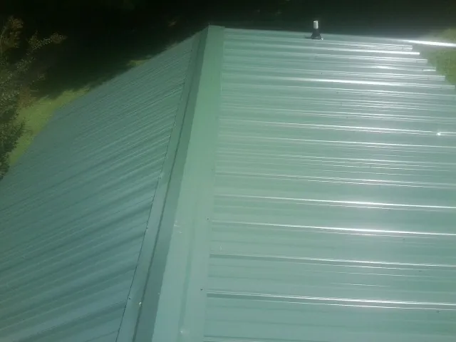New green metal panels meeting at the ridge of a roof — Flat Roof Repair work by our crew in Lynnwood