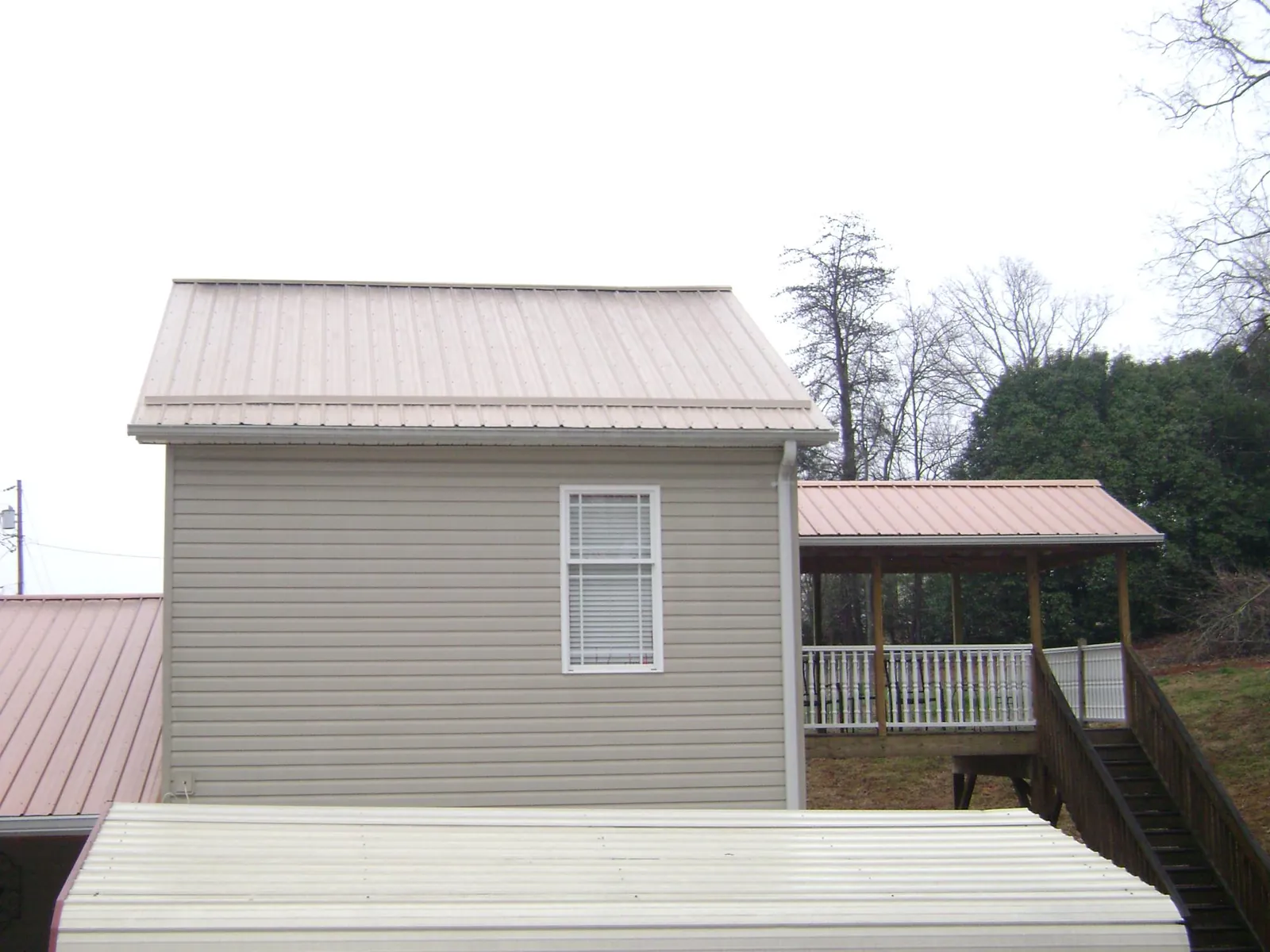 Tan metal roofs on a two story addition and attached porch, from a Roof Replacement job in Lynnwood