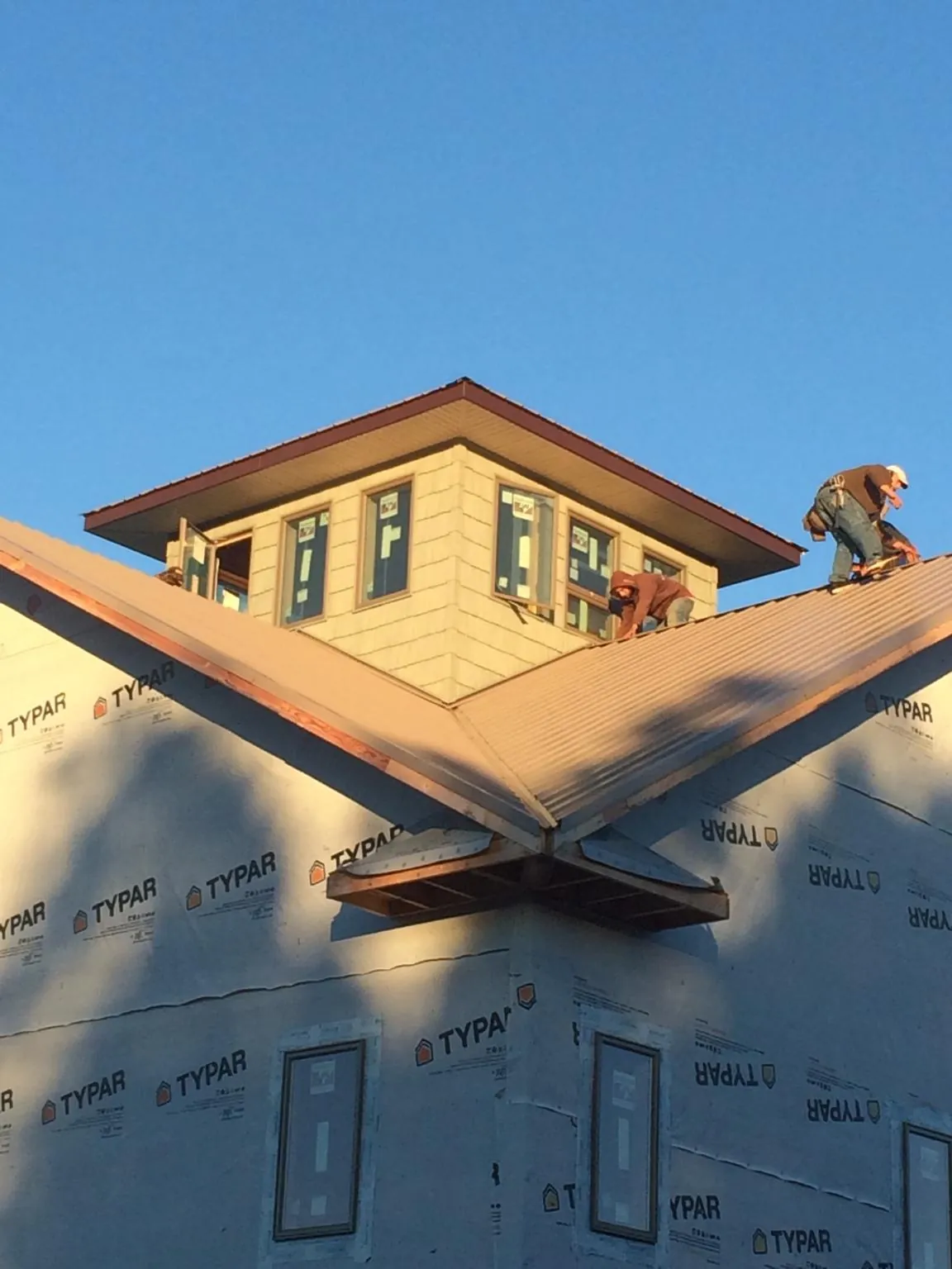 Roofers working around a rooftop cupola on a new metal roof at sunset — Roof Waterproofing in Lynnwood by Roofing Brothers